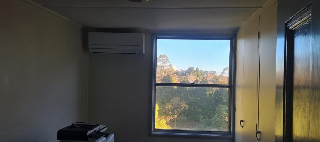 Small room with a split-system air conditioner installed above a large window