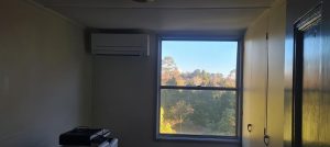 Small room with a split-system air conditioner installed above a large window